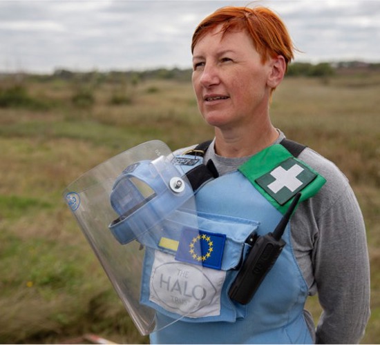 Viktoria, stands in a field wearing PPE