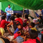 A member from the explosive ordnance risk education team speaks to adults and children outside
