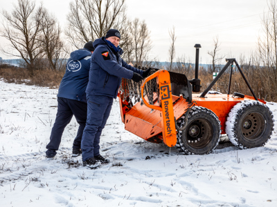 Two HALO staff stand next to a mechanical asset at a training ground in Kyiv region