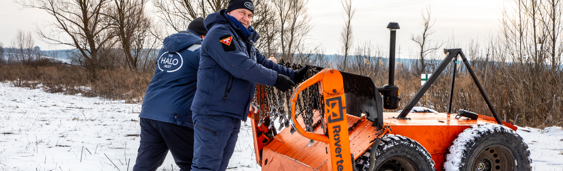 Two HALO staff stand next to a mechanical asset at a training ground in Kyiv region