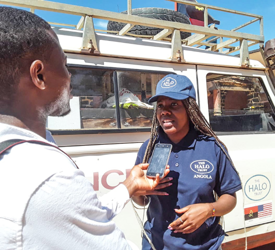 Felicia Pandassala, Programme Officer in HALO Angola, speaks into a phone held by an interviewer