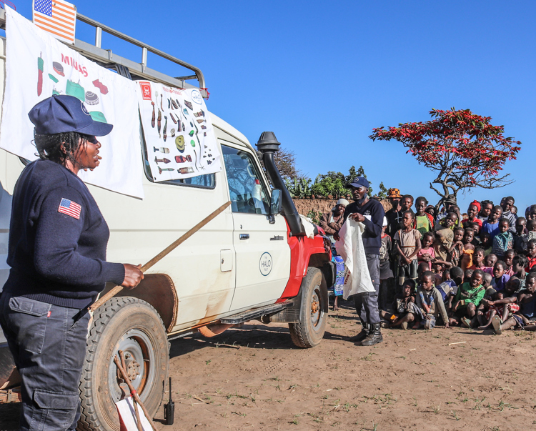 A HALO staff member delivers an EORE session pointing to a banner on a vehicle