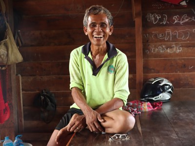 Ouk, a farmer from Cambodia smiles while sitting on a bench