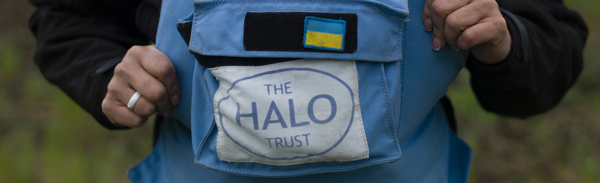 A light blue HALO Trust vest with the Ukrainian flag above it.