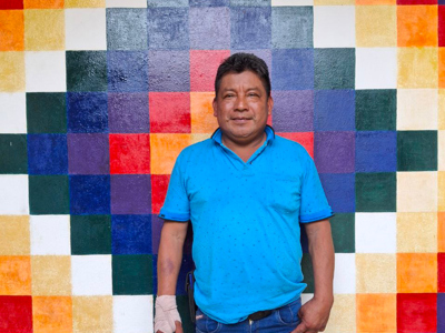 A middle-aged man wearing a blue polo stands in front of a colorful geometric mural.