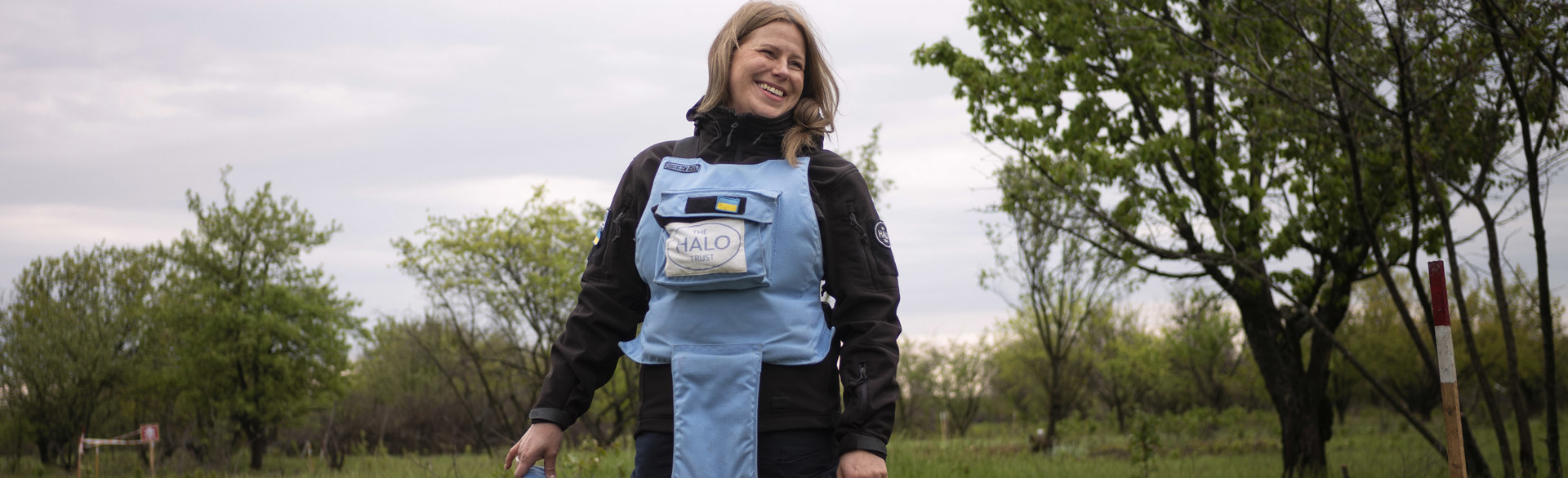 Ukrainian deminer smiling in the field while wearing PPE