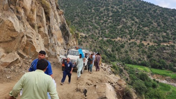 Trucks and personnel travel up a mountainside in Afghanistan.