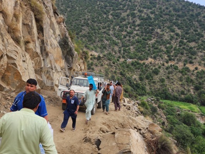 Trucks and personnel travel up a mountainside in Afghanistan.