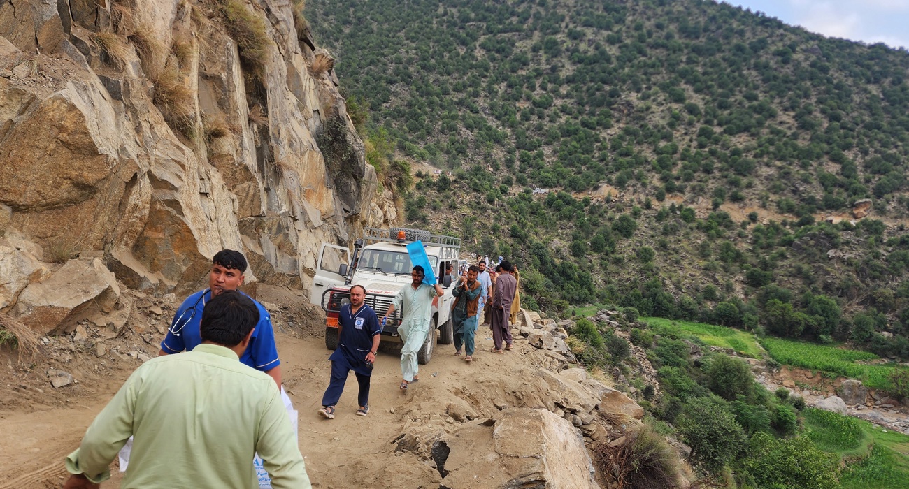 Trucks and personnel travel up a mountainside in Afghanistan.