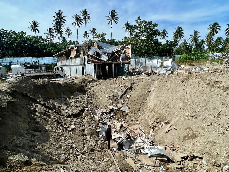 A crater left with debris outside a destroyed building