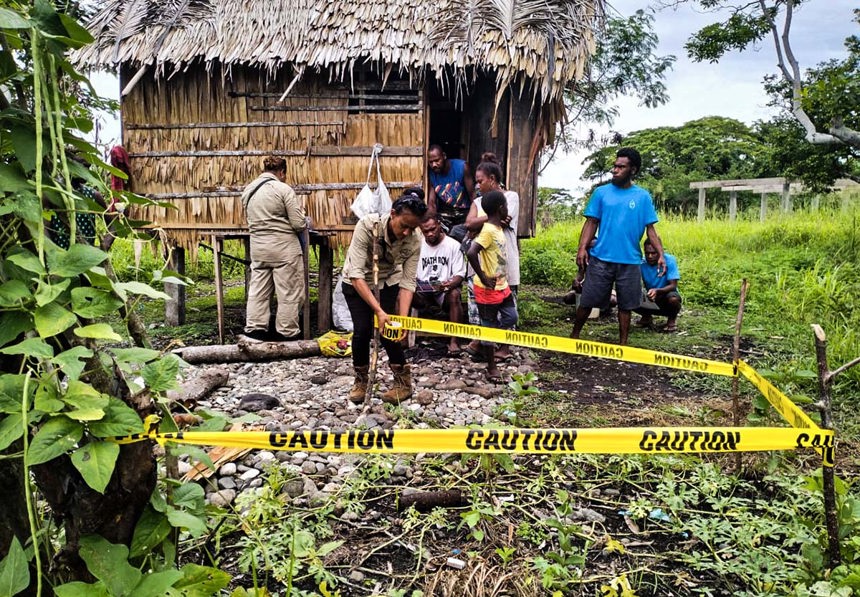 A HALO staff member wraps caution tape around a small area of land outside a families home