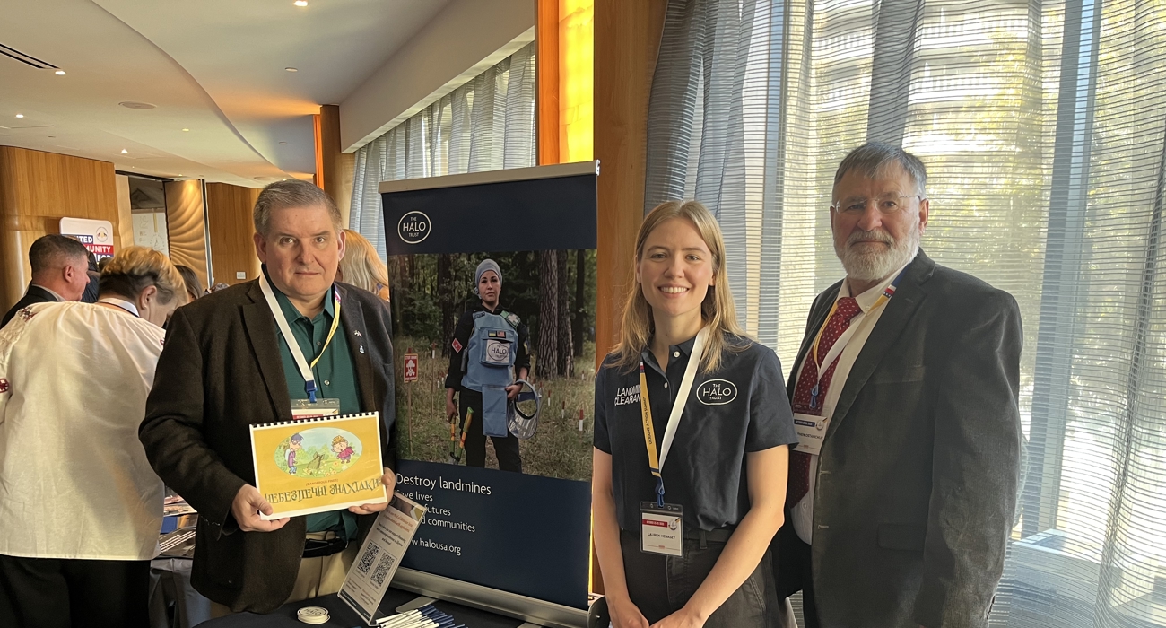 Three people pose for a photo at an exposition booth.