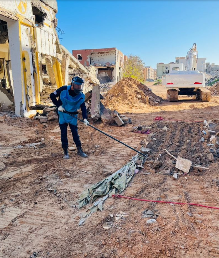 A deminer rakes through rubble in Sirte, Libyra