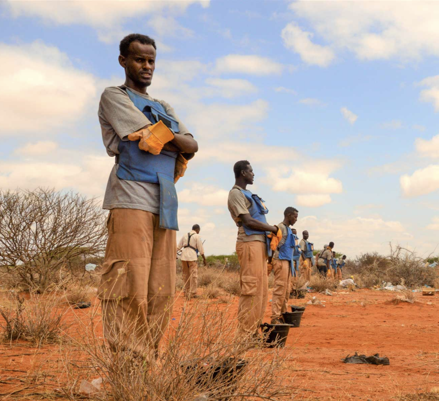 HALO deminers stand in line for battle area clearance with small black buckets in front of them