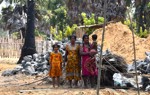Two women, a young girl, and a toddler in colorful dresses stand in front of a pile of rocks.