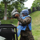 A HALO Trust Weapons and Ammunition technician holds a large sandbag whilst wearing a protective helmet and visor