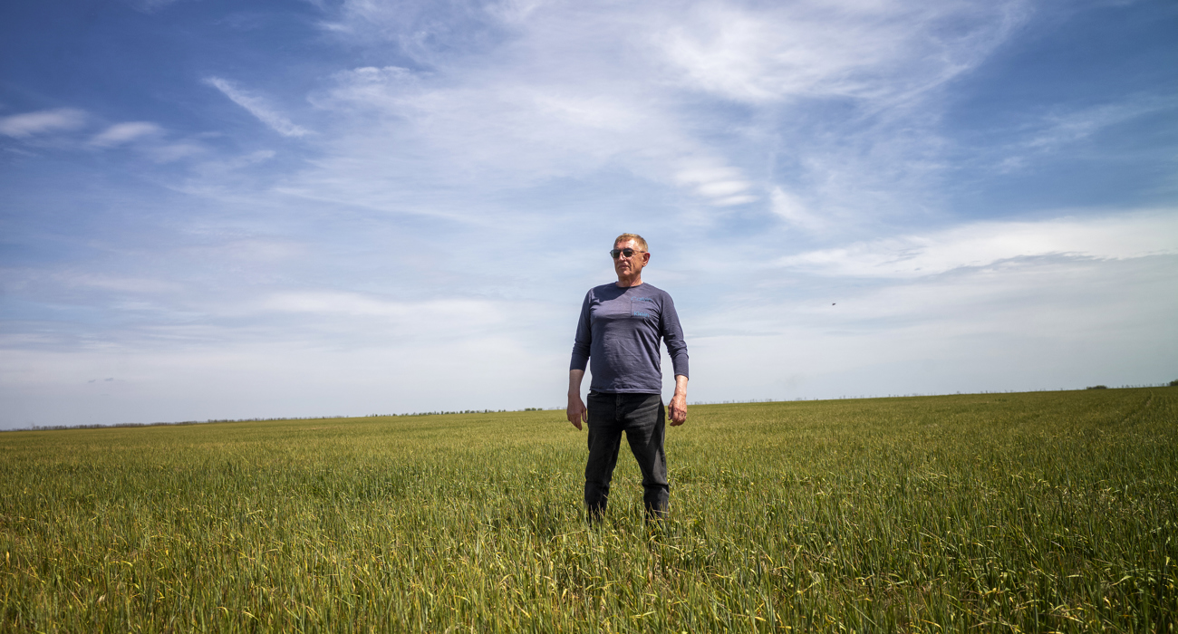 A man in sunglasses stands in the middle of a green field.