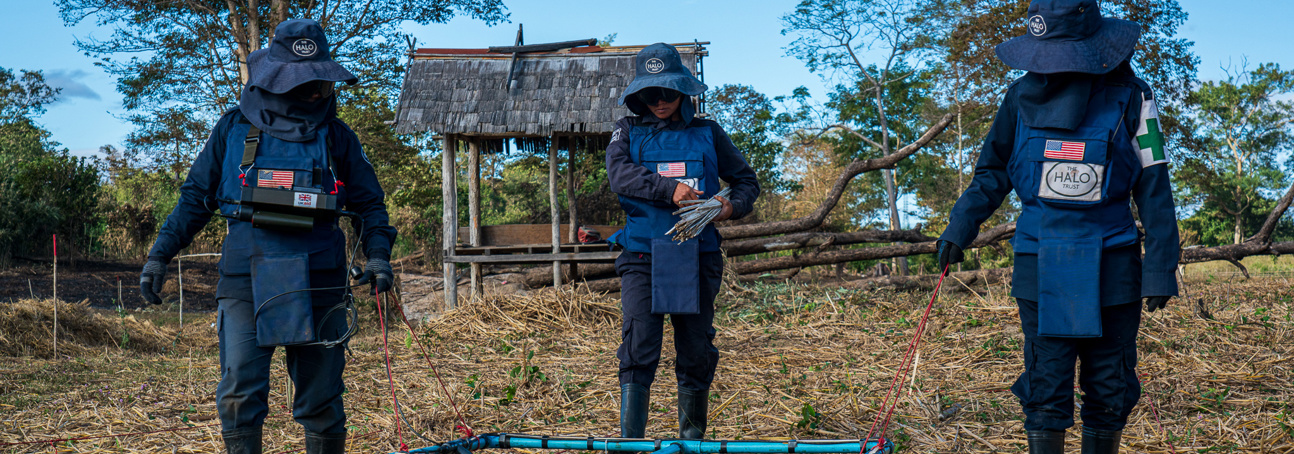 Three deminers carry out manual demining activities in Laos