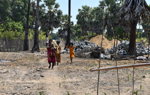 Two women, a young girl, and a toddler walk away from a pile of rocks.