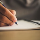 A hand holds a pen over a piece of paper