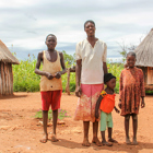 A family stands outside some huts in katia village