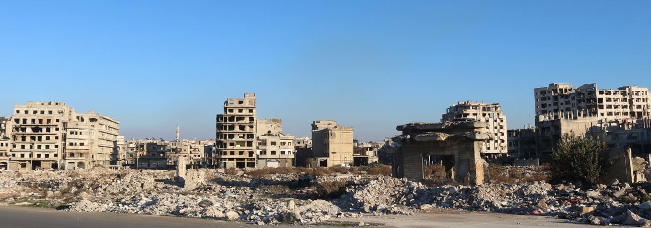 A landscape view of damaged buildings with rubble scattered around them