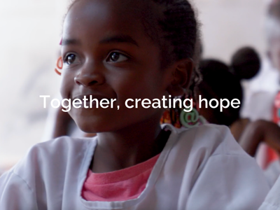 A young girl sits, smiling in a classroom