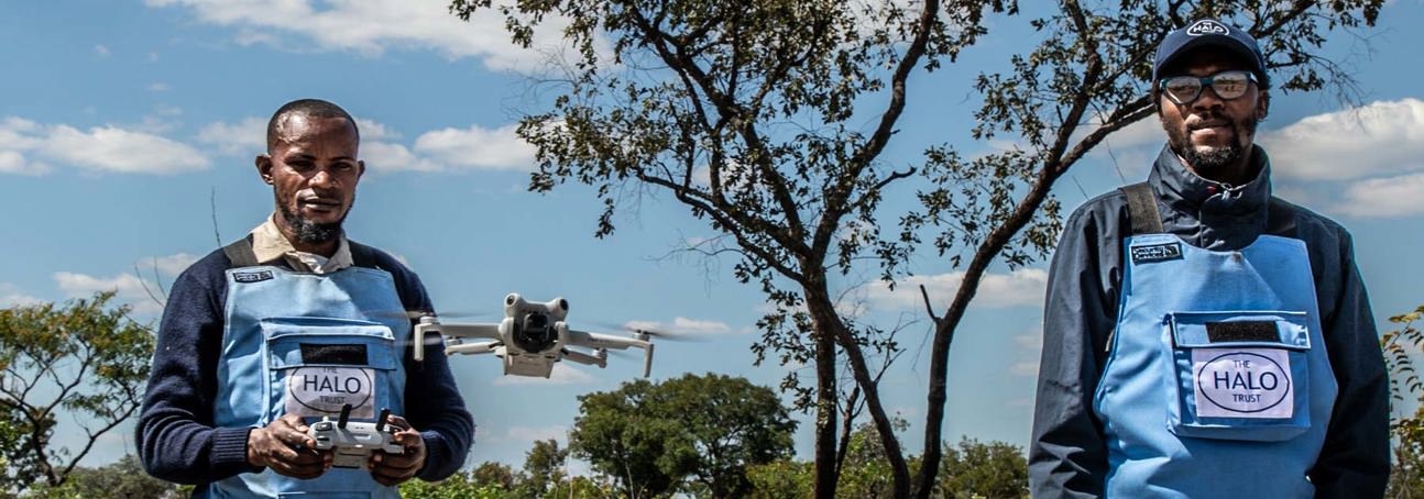 Two HALO Deminers wear PPE while flying a drone in Angola