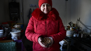 A woman in red coat and red hat stands holding a handful of hazelnuts