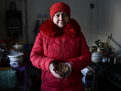 A woman in red coat and red hat stands holding a handful of hazelnuts