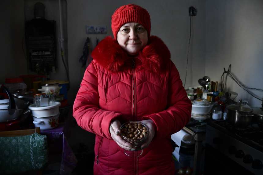 A woman in red coat and red hat stands holding a handful of hazelnuts