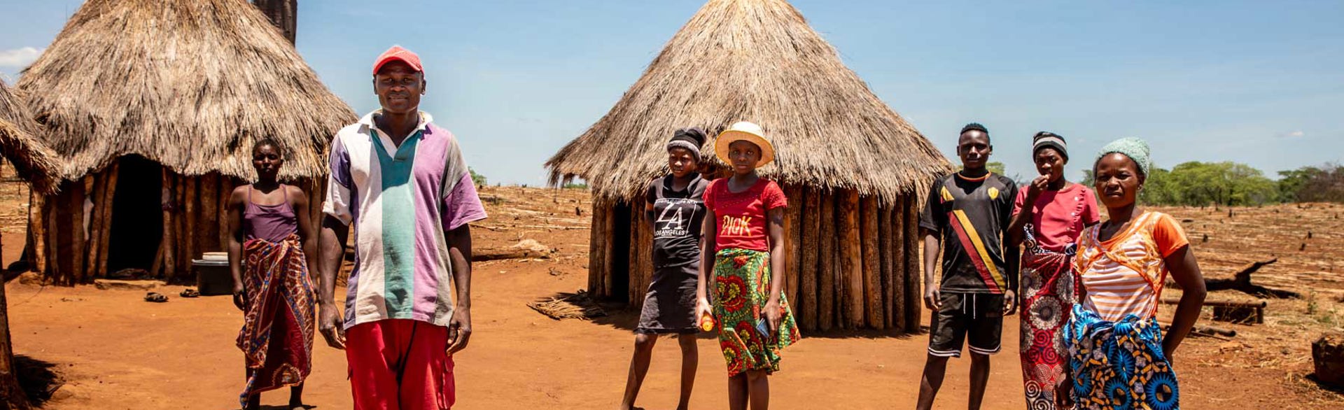 A group of Zimbabwean villagers stand on the ground outside their houses