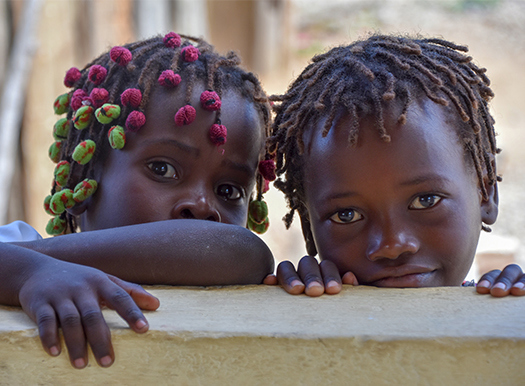 Two children peak over a banister